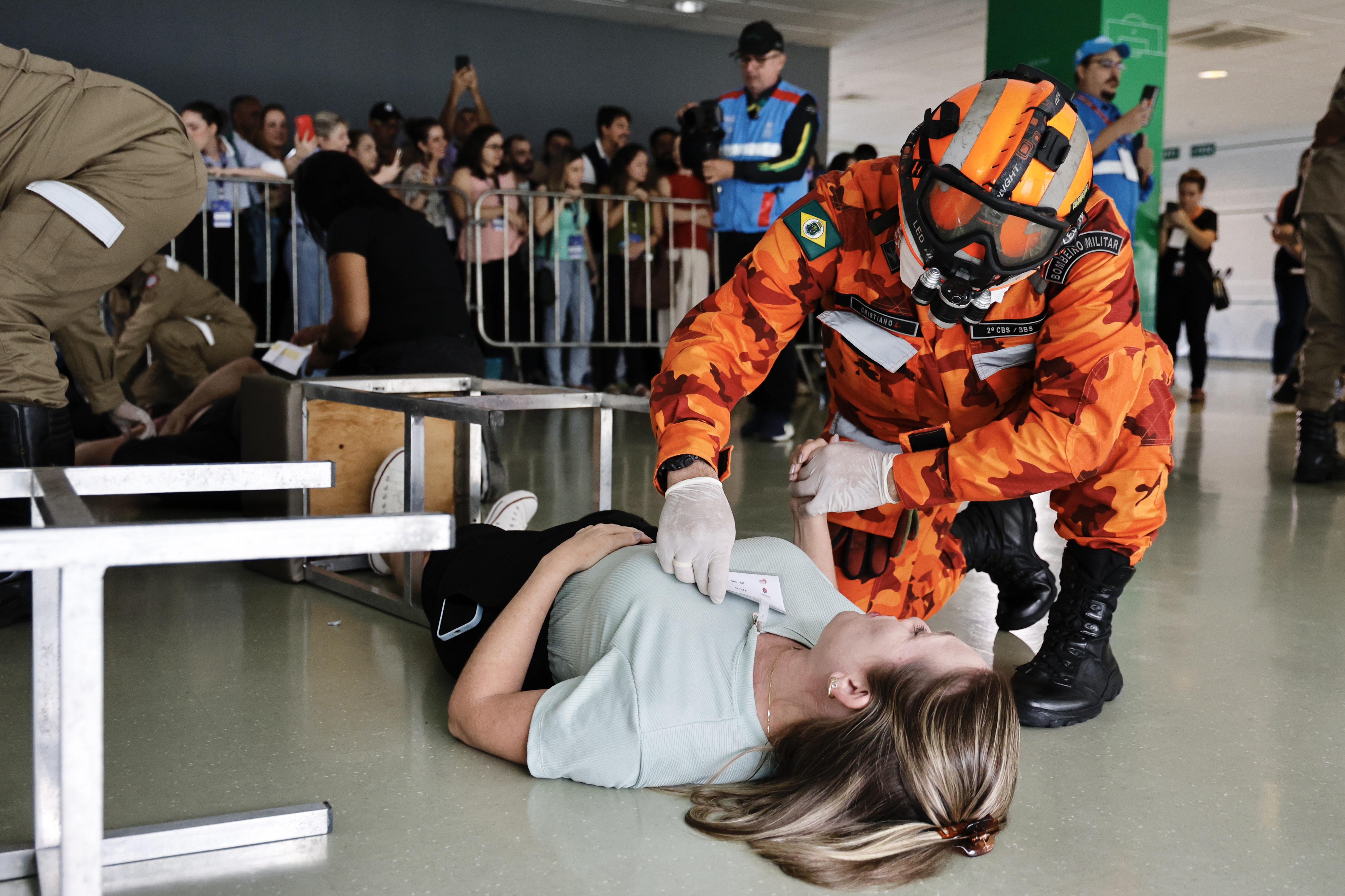 atendente do SUS e conversa com uma mulher deitada no chão durante a simulação de acidente